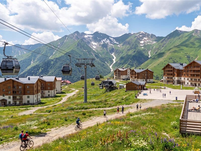 A mountain biker on a track through summer meadow below the Gudauri gondola
