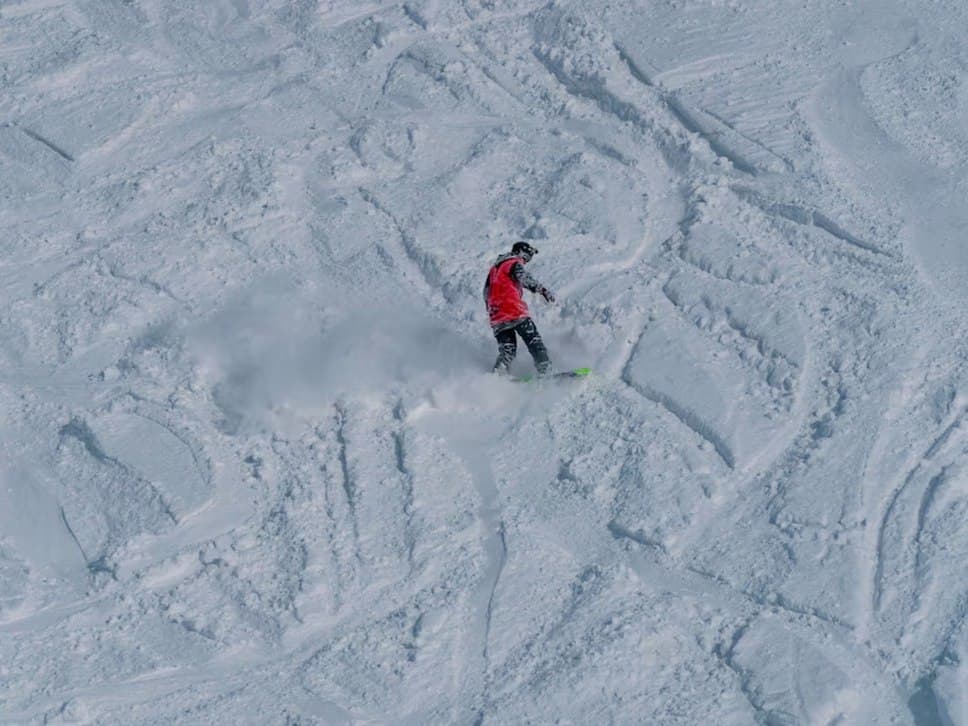 A skier carving down a tracked piste above New Gudauri